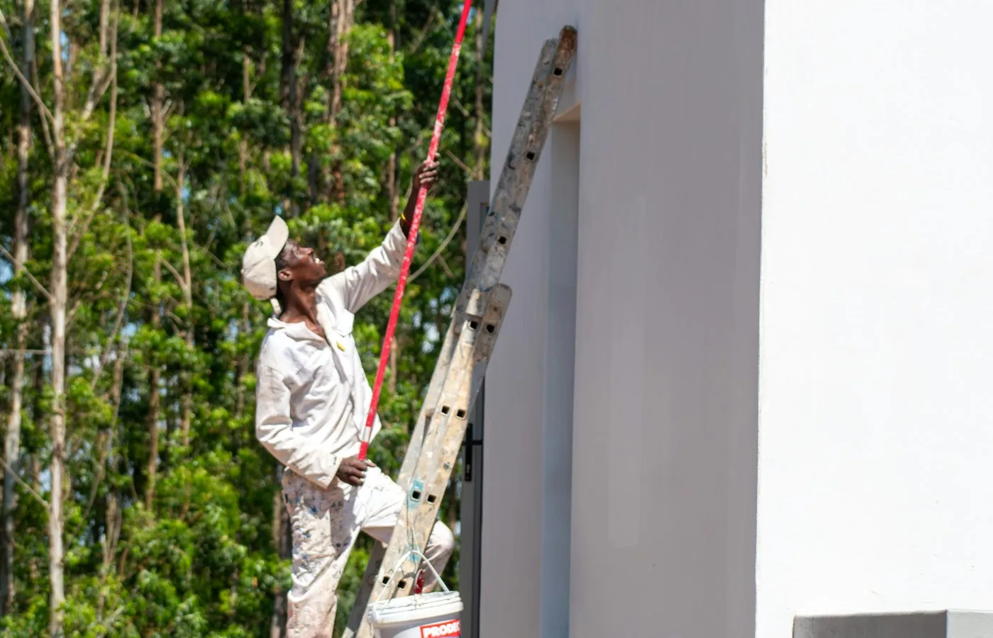 Professional painter on a ladder painting the exterior of a house